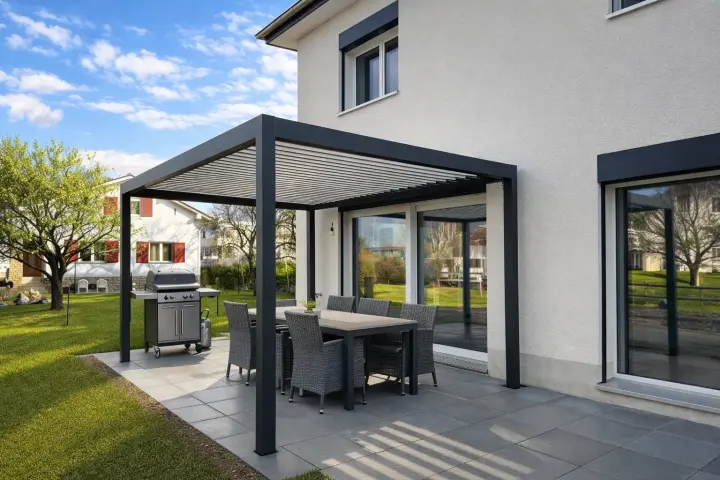Terrasse sous la pergola bioclimatique, avec table et barbecue.